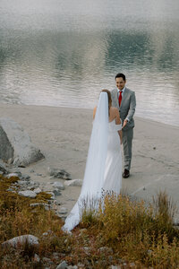 Portrait of bride and groom looking at each other by a lake in Whistler BC