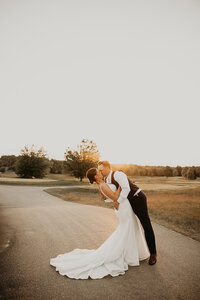 In the enchanting woods, the groom tenderly tilted the bride and sealed the moment with a kiss.