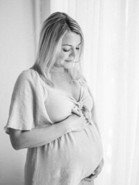 black and white image of a pregnant woman looking down at her belly