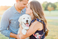 engaged couple poses for photos with their puppy