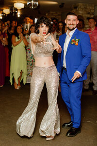 Bride and groom on dancefloor in seventies style outfits in editorial wedding photo