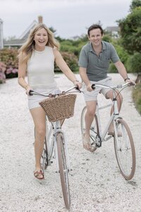 Couple smile as they ride bikes through Wauwinet, Nantucket.