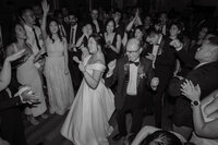 Mariée dansant avec son père entourée d'invités en liesse à la Gare Viger, ambiance festive et spontanée en noir et blanc, moment de célébration familiale
