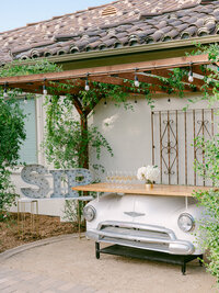 A refined luxury estate wedding in Temecula featuring a meticulously restored 1950s vintage automobile provided by Madam Palooza, set against rolling vineyard landscapes and elegant architectural details. The classic car adds a timeless, old-world glamour to the celebration, complementing the sophisticated design and elevated aesthetic of a private estate wedding curated for discerning clients