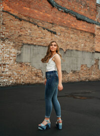 Senior portrait in downtown Mobile, Alabama — twirling her hair with a white tank top and blue jeans.