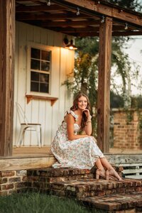 Senior portrait in downtown Magnolia Springs, Alabama — posing on a porch under a light.