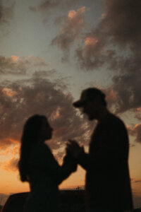 Guy and girl holding hands at sunset silhouette
