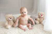 A six month old baby boy posed with stuffed animals during his studio Milestone session by Jennifer Brandes Photography.