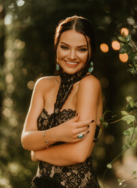 Senior portrait at Triple T Farms in Fruitdale, Alabama — smiling in a black lace dress with teal
earrings and a teal ring.