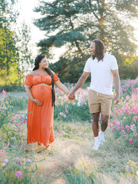 An expecting couple walking hand in hand and looking at each other lovingly in their maternity photo session in Seattle