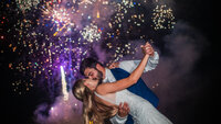 A newly wedding couple kissing under fireworks