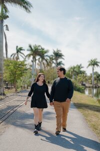 Engaged couple walking hand-in-hand in Lakes Park, Fort Myers Florida.
