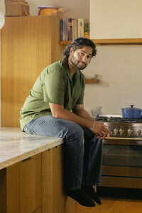 Man seated on a kitchen counter in warm daylight