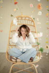 woman sits on boho chair in floral installation at studiostudio in ann arbor michigan