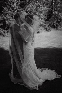 Moment intime capturé en noir et blanc d’un couple enlacé sous un voile de mariée, sur la Rive-Sud de Montréal, par Jeff Gagnon photographe.