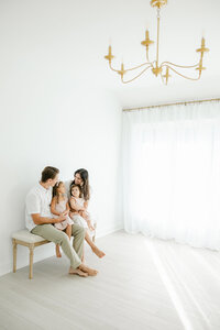 family of 4 sitting on bench in studio