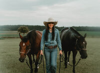 Senior portrait at Triple T Farms in Fruitdale, Alabama — walking toward the camera while
leading two horses.