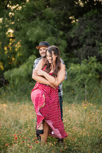 Playful interaction between engaged couple having a tickle fight during a portrait session in Burleson.