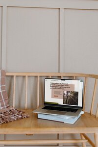 An open laptop sits on a bench displaying its homepage design, representing copywriting and web design services by Bloem Creations.