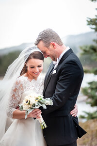 A Bride and Groom Embrace with Big Smiles Just After Their First Look While It Snows on Them