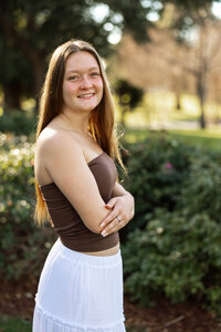 High school senior girl standing in a garden setting with soft natural light, lifestyle senior portrait by Kaitlyn Dawn Photography.