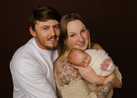 Parents holding their newborn baby together during a studio family portrait. Photographed by Inland Empire newborn photographer Kaitlyn Dawn Photography.