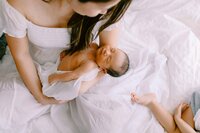 newborn son being held by his mom while his sister's foot sticks into the photo
