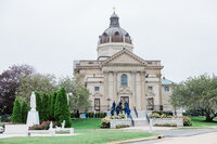 A grand, historic church-style venue with a domed roof and classical architecture. Guests in suits and dresses walk up the steps, ready to celebrate the couple’s wedding day.