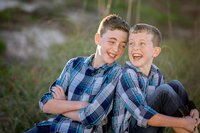 Ponte Vedra portrait session capturing On Beach, two brothers lean against each other, laughing mid-joke during a relaxed outdoor child portrait session.