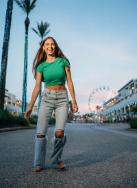 Senior portrait at The Wharf in Orange Beach, Alabama — laughing while dancing in the street
with the Ferris wheel behind her.