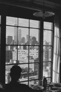 Man looking out of the window of a hotel at the skyline of New York City