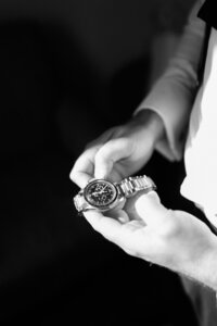 Groom holds his watch in front of a sunlit window