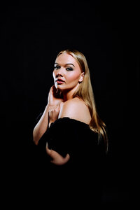 Woman in black posed against a dark background for a dramatic editorial portrait