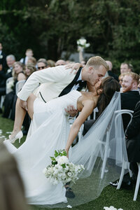 groom dips bride romantically walking down the wedding aisle