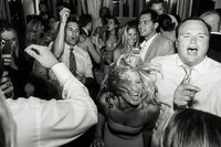 A high-energy, documentary style wedding photography capture of guests dancing and singing at a luxury coastal reception.