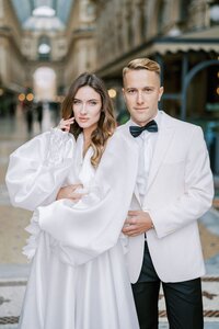 smiling-groom-hugs-bride-waist-stand-galleria-vittorio-emanuele-ii-milan-italy