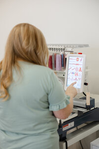 Woman reviewing embroidered fabric designs while seated at a table. Photograph by Yucaipa branding photographer Kaitlyn Dawn Photography.