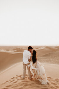 bride and groom walking in sand dunes