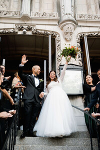 A documentary style wedding photography capture of a couple cheering as they exit St. Vincent Ferrer in New York City.