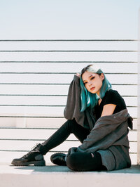 Fashion-forward portrait of a woman posed against a bright neutral backdrop.