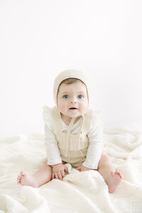 sitter sessoin for little girl with brown hair wearing bonnett