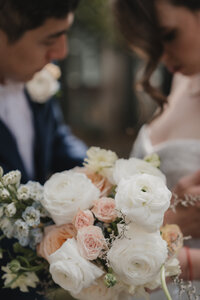 Détail poétique d’un bouquet de mariée aux teintes douces, avec un couple en arrière-plan, capturé lors d’un mariage au Centre des sciences de Montréal — instant d’émotion saisi par un photographe de mariage à Montréal.