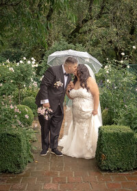 Couple after their wedding stealing kisses in the rain at Deepwood Museum & Gardens in Salem Oregon