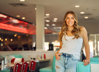 Senior portrait at Sunliner Diner in Gulf Shores, Alabama — waist-up beside the booth with a
finger hooked in a belt loop.