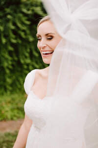 candid laughing bride with veil flowing in the wind at wilburn street studio nashville wedding