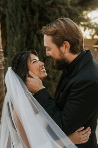 A married couple smiling at each other as they lean in to kiss 