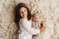 Newborn Pictures in Charleston - Siblings embrace their infant baby brother during Newborn Pictures at Holy City Babies Newborn Photography Studio in Charleston, SC.