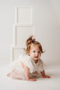 Charleston Cake Smash Photographer- Baby looks into the camera during Milestone Portraits at Holy City Babies Portrait Studio in Charleston, SC.