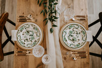 two china plates on a wood table with a cream table runner
