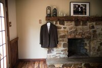 a groom's suit jacket hanging from a stone fireplace mantle